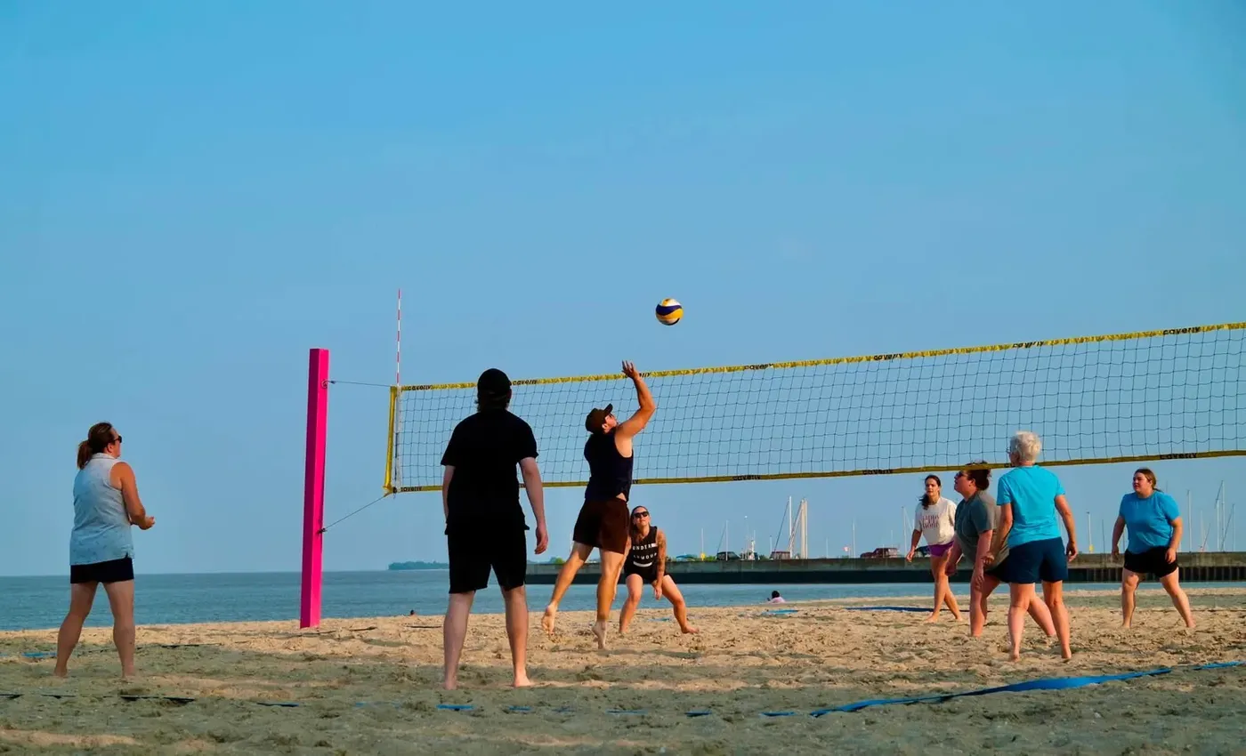 Beach volleyball players watching a ball above the net beside Lake Winnipeg in Gimli